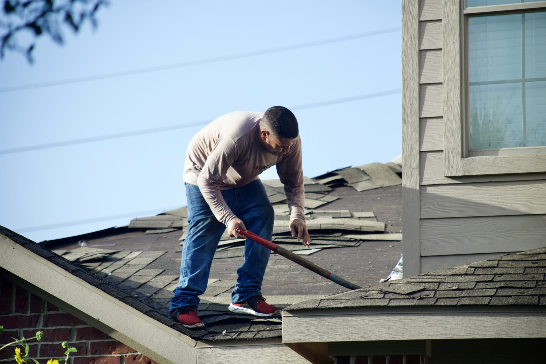 Roofer with hammer working on a shingle roof in Orange County